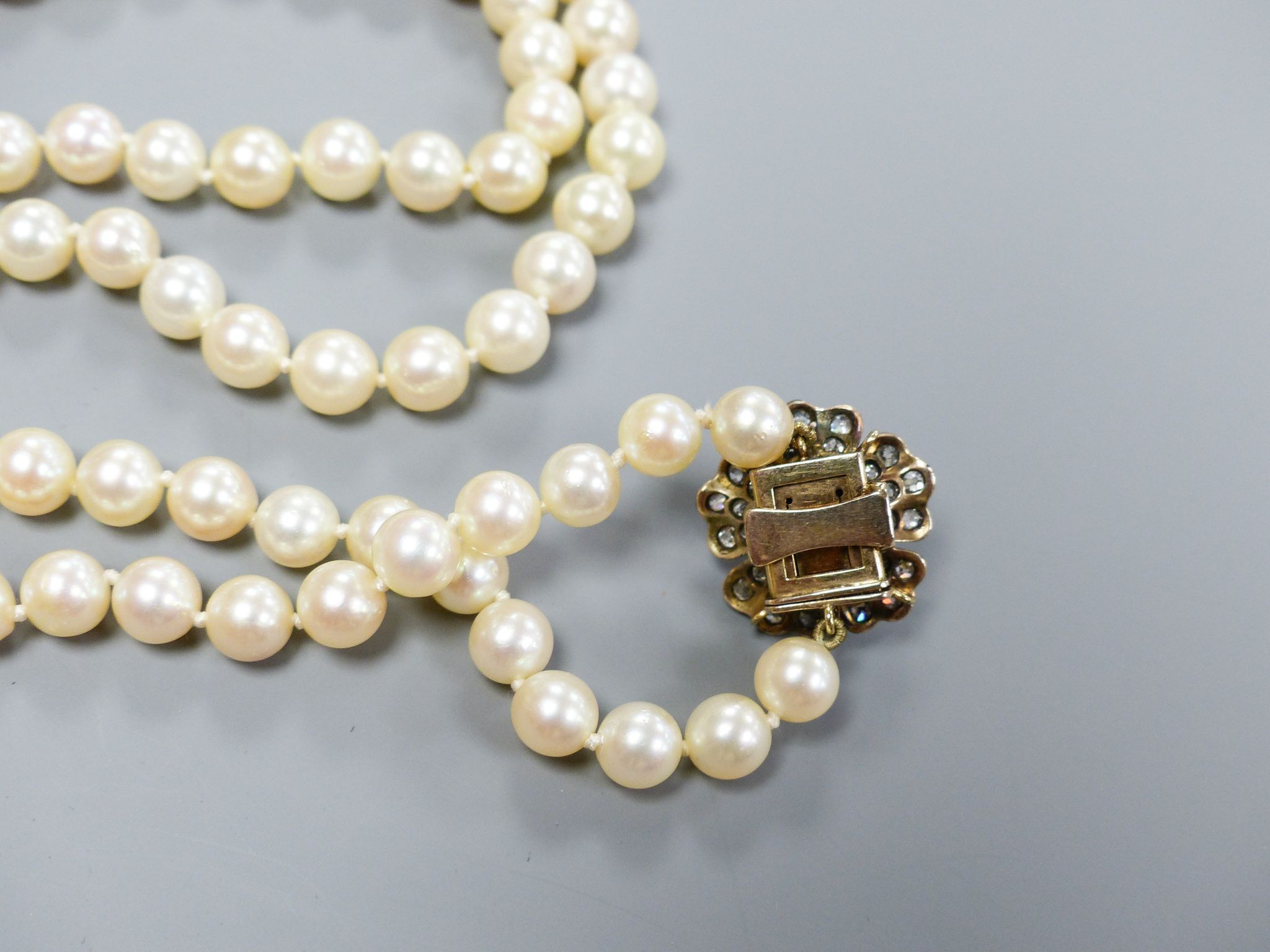 A single strand graduated cultured pearl necklace, with yellow metal, diamond and cultured pearl set flower head cluster clasp, 76cm, largest pearl diameter 94mm, gross weight 66 grams.